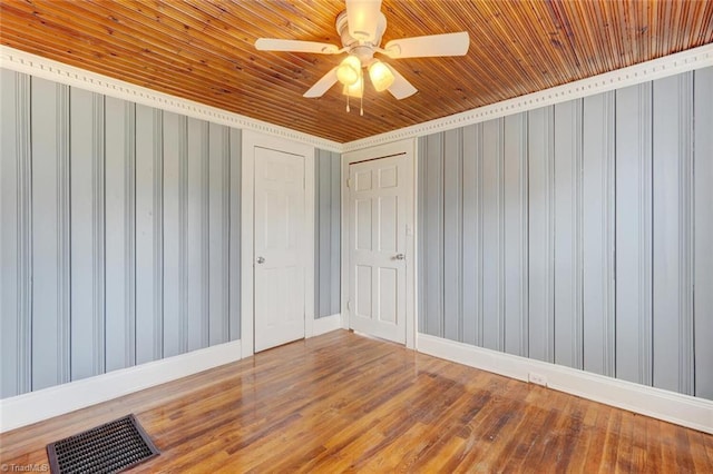 empty room with visible vents, wood ceiling, baseboards, and wood finished floors