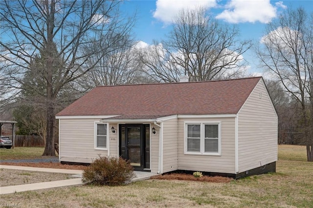 view of front of home with a chimney, a front lawn, and a shingled roof