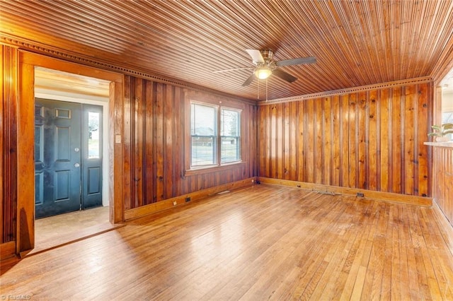 unfurnished room featuring a ceiling fan, baseboards, wood ceiling, wood walls, and light wood-type flooring