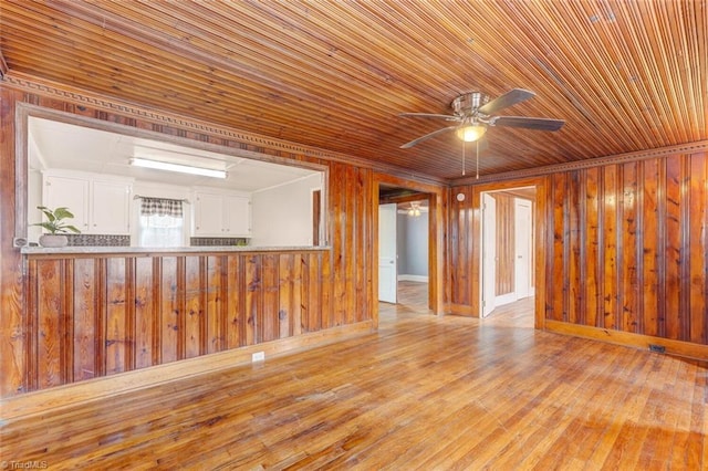 empty room with ornamental molding, a ceiling fan, hardwood / wood-style flooring, wooden ceiling, and wood walls