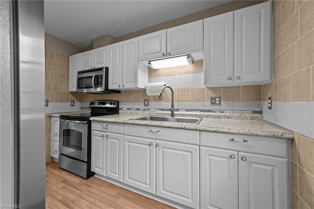 131 Springdale Dr, Stoneville, NC 27048 - kitchen with white cabinets, a sink, light wood-style flooring, stainless steel appliances, and tile walls