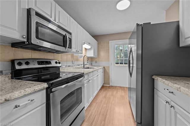 131 Springdale Dr, Stoneville, NC 27048 - kitchen with a textured ceiling, appliances with stainless steel finishes, a sink, light wood finished floors, and white cabinetry