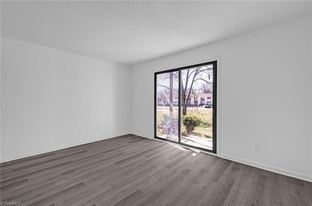 empty room featuring baseboards, dark wood-type flooring, and a textured ceiling