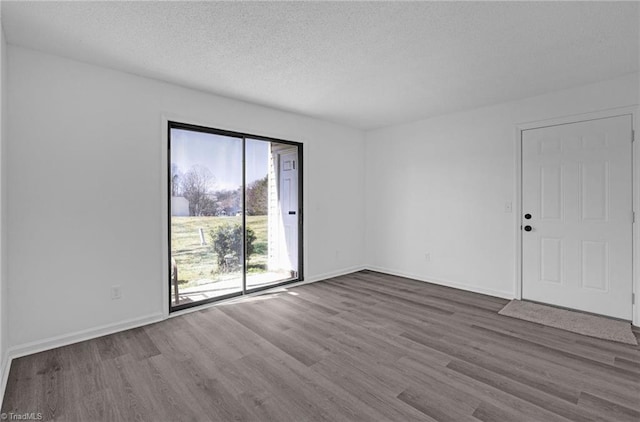 unfurnished room featuring baseboards, dark wood-style flooring, and a textured ceiling