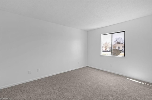 unfurnished room with a textured ceiling, baseboards, and carpet floors