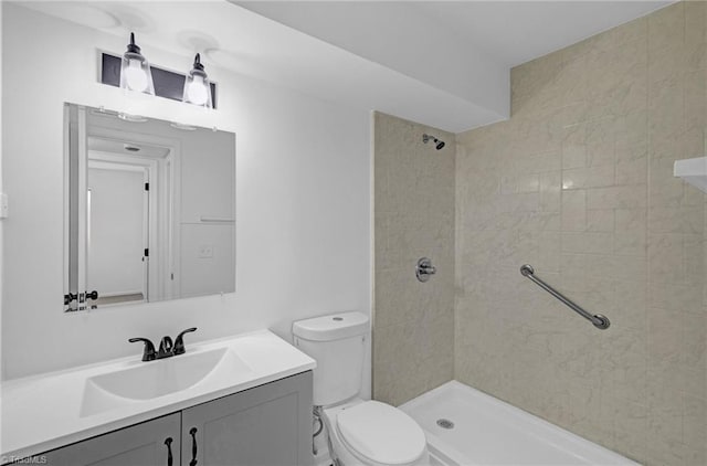 bathroom featuring vanity, toilet, and tiled shower