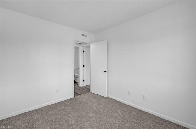 spare room with carpet, visible vents, and baseboards