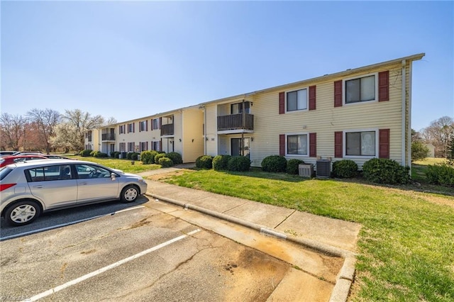 view of front of property with a front lawn, central air condition unit, and uncovered parking