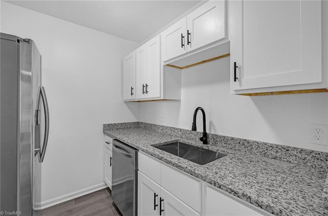 kitchen with a sink, dark wood-style floors, white cabinetry, appliances with stainless steel finishes, and light stone countertops