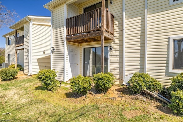 view of side of property with central air condition unit, a balcony, and a yard