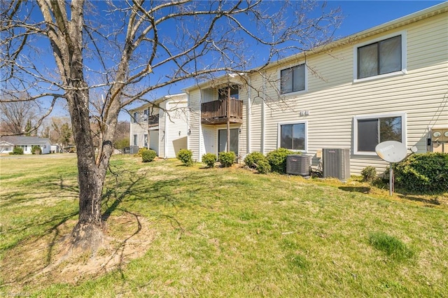 back of property with a balcony, cooling unit, and a lawn