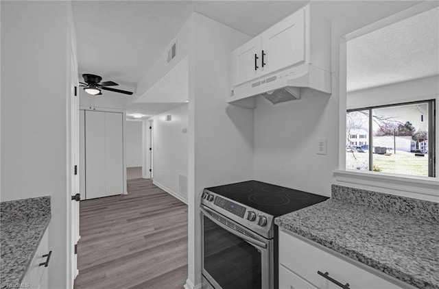 kitchen featuring under cabinet range hood, light stone countertops, stainless steel electric range, and white cabinets