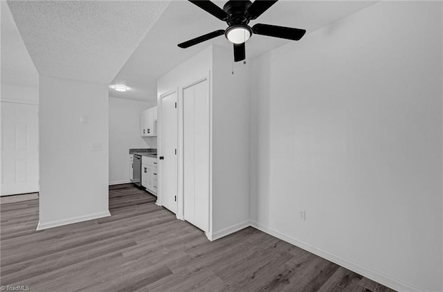 unfurnished living room with baseboards, a textured ceiling, wood finished floors, and a ceiling fan