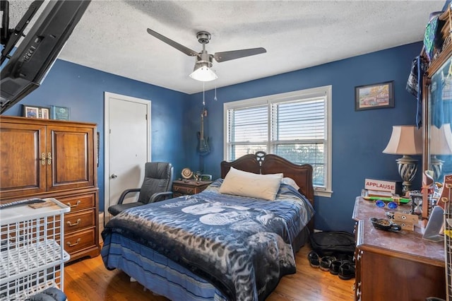 bedroom featuring hardwood / wood-style floors, a textured ceiling, and ceiling fan