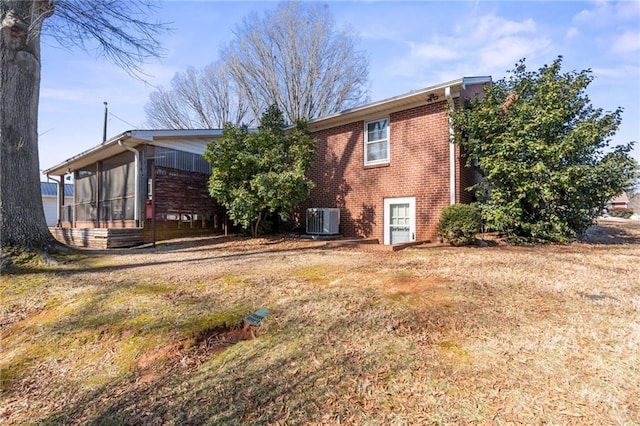 rear view of property with a sunroom, cooling unit, and a lawn