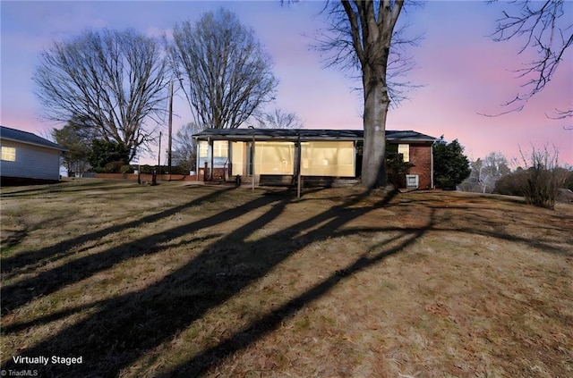 back house at dusk with a lawn