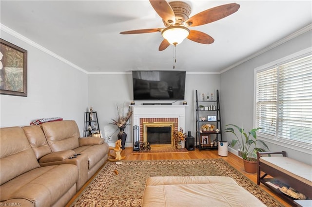 living room featuring crown molding, ceiling fan, light hardwood / wood-style floors, and a brick fireplace