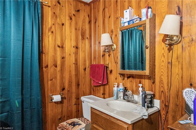 bathroom with vanity, wooden walls, and toilet