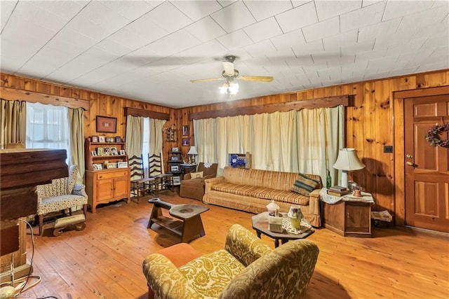 living room with hardwood / wood-style flooring, ceiling fan, and wooden walls