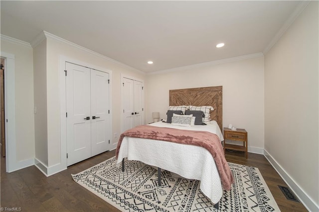 bedroom with dark wood-style floors, two closets, crown molding, recessed lighting, and baseboards