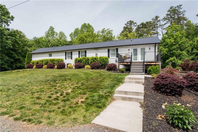 ranch-style home with a front yard, metal roof, stairway, and a deck