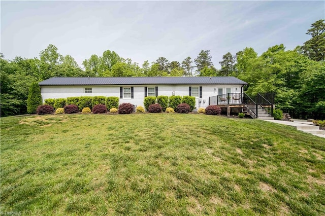 view of front of house with a wooden deck, metal roof, and a front yard