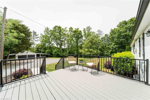 wooden deck featuring view of scattered trees, an outbuilding, and a detached garage