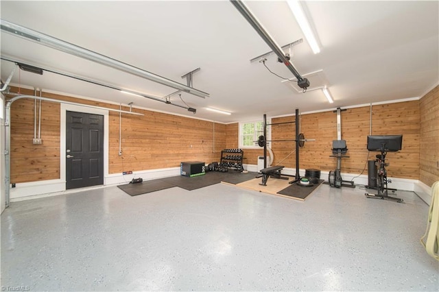 garage featuring wooden walls, a garage door opener, and baseboards