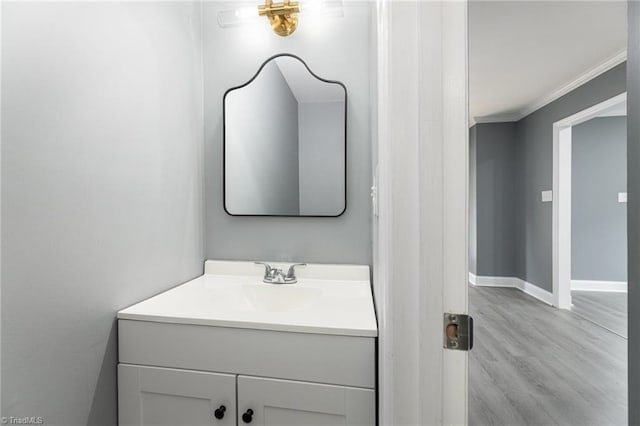 bathroom with crown molding, vanity, and hardwood / wood-style flooring