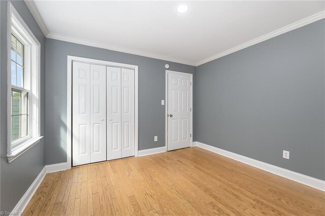 unfurnished bedroom featuring ornamental molding, a closet, and light hardwood / wood-style floors