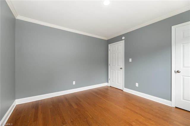 empty room with wood-type flooring and crown molding