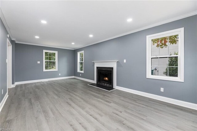 unfurnished living room featuring light wood-type flooring, a healthy amount of sunlight, and crown molding