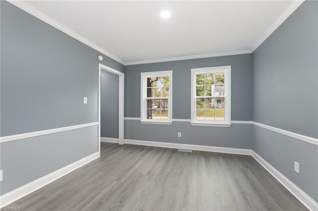 spare room featuring ornamental molding and light hardwood / wood-style floors