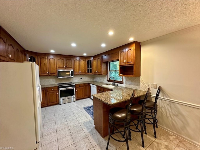 3501 River Ridge Rd, Pfafftown, NC 27040 - kitchen featuring stainless steel appliances, a sink, a peninsula, backsplash, and a textured ceiling