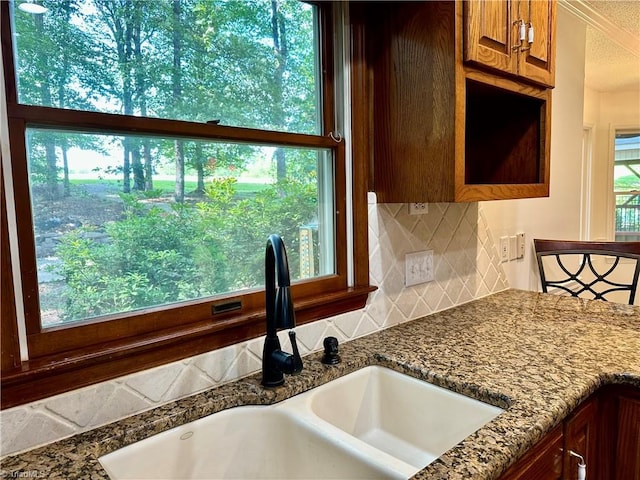 3501 River Ridge Rd, Pfafftown, NC 27040 - kitchen featuring a sink, decorative backsplash, brown cabinets, a textured ceiling, and dark stone countertops