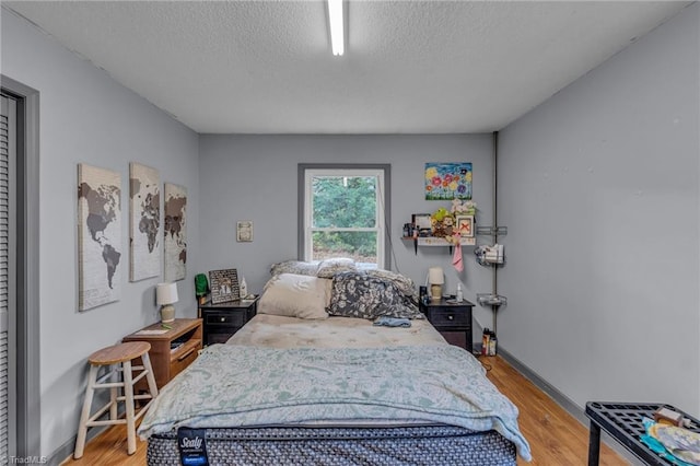 bedroom with a textured ceiling and light hardwood / wood-style floors