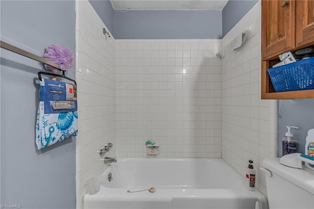 bathroom featuring toilet, tiled shower / bath combo, and a textured ceiling