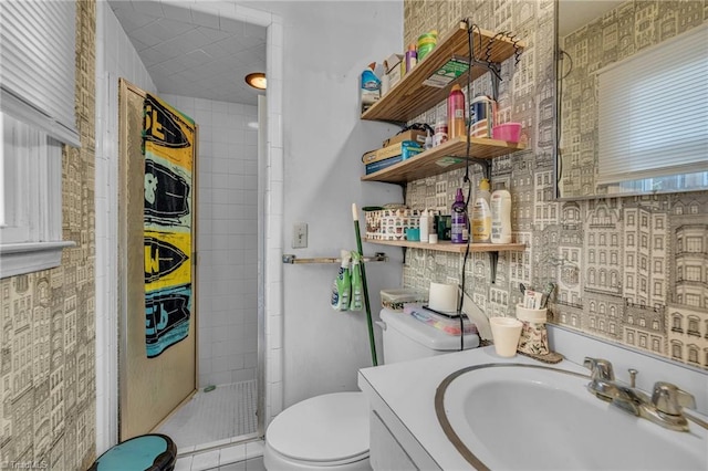 bathroom featuring tile patterned flooring, tiled shower, toilet, and vanity