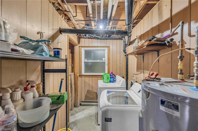 laundry room with electric water heater, washer and dryer, and wood walls