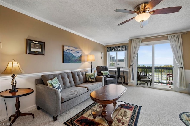 living room featuring a textured ceiling, ceiling fan, carpet flooring, and crown molding