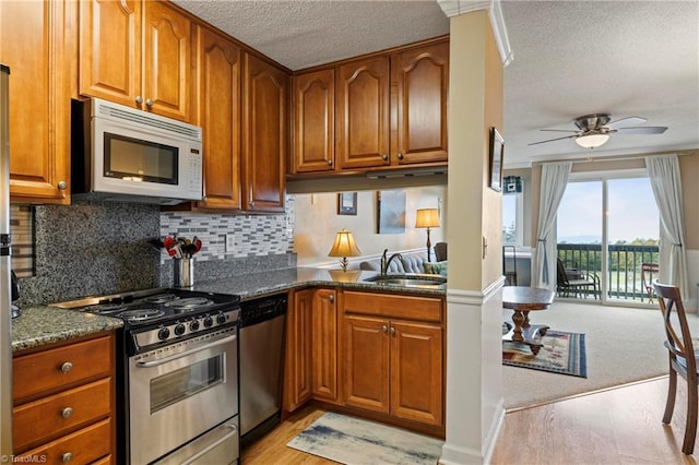 kitchen with a textured ceiling, ceiling fan, appliances with stainless steel finishes, and dark stone countertops