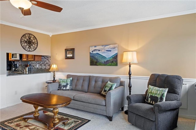 carpeted living room featuring ceiling fan and ornamental molding