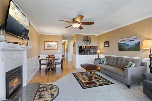 living room featuring ceiling fan with notable chandelier, crown molding, and light hardwood / wood-style floors