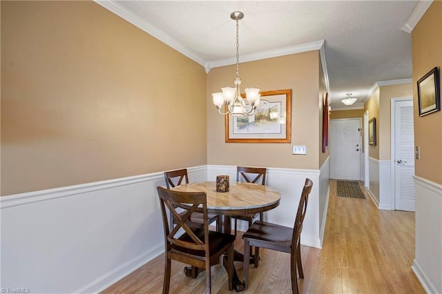 dining room with a notable chandelier, ornamental molding, and light hardwood / wood-style flooring