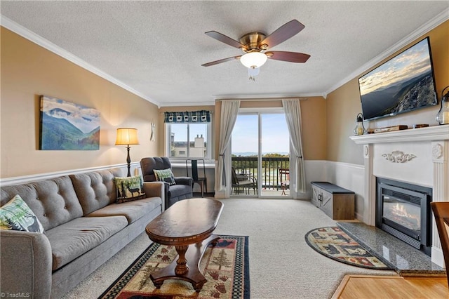 carpeted living room featuring ceiling fan, a textured ceiling, and crown molding