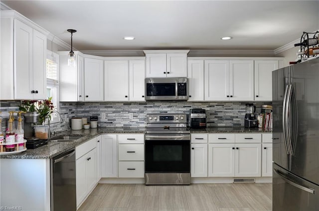 kitchen featuring decorative backsplash, appliances with stainless steel finishes, dark stone counters, sink, and white cabinetry