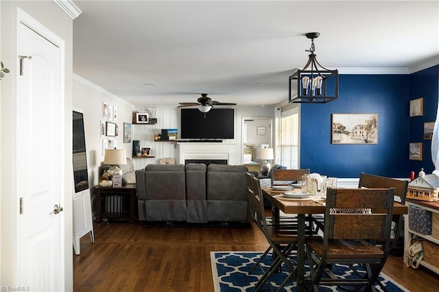 dining area featuring dark hardwood / wood-style flooring, ceiling fan with notable chandelier, and crown molding