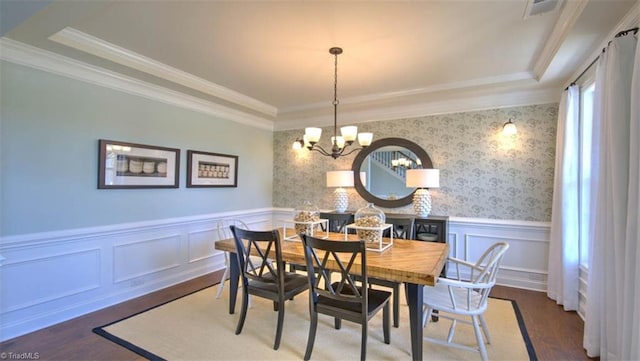 dining room with a notable chandelier, ornamental molding, and dark hardwood / wood-style flooring