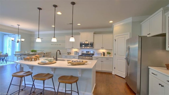 kitchen featuring a kitchen island with sink, dark hardwood / wood-style floors, hanging light fixtures, appliances with stainless steel finishes, and a kitchen bar