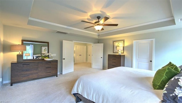 bedroom featuring ceiling fan, a tray ceiling, light carpet, and crown molding